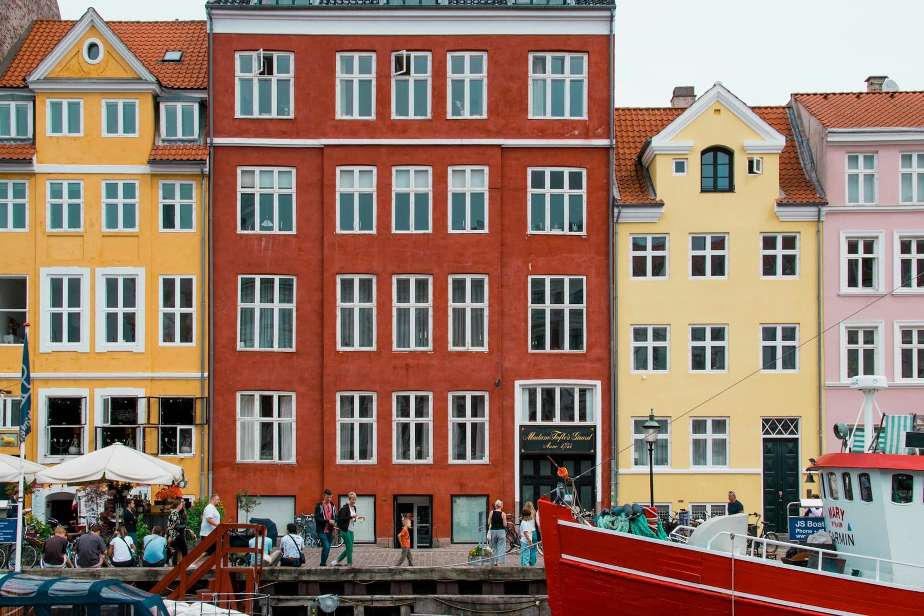 قارب أحمر أمام صف المنازل الملوّنة على قناة Nyhavn