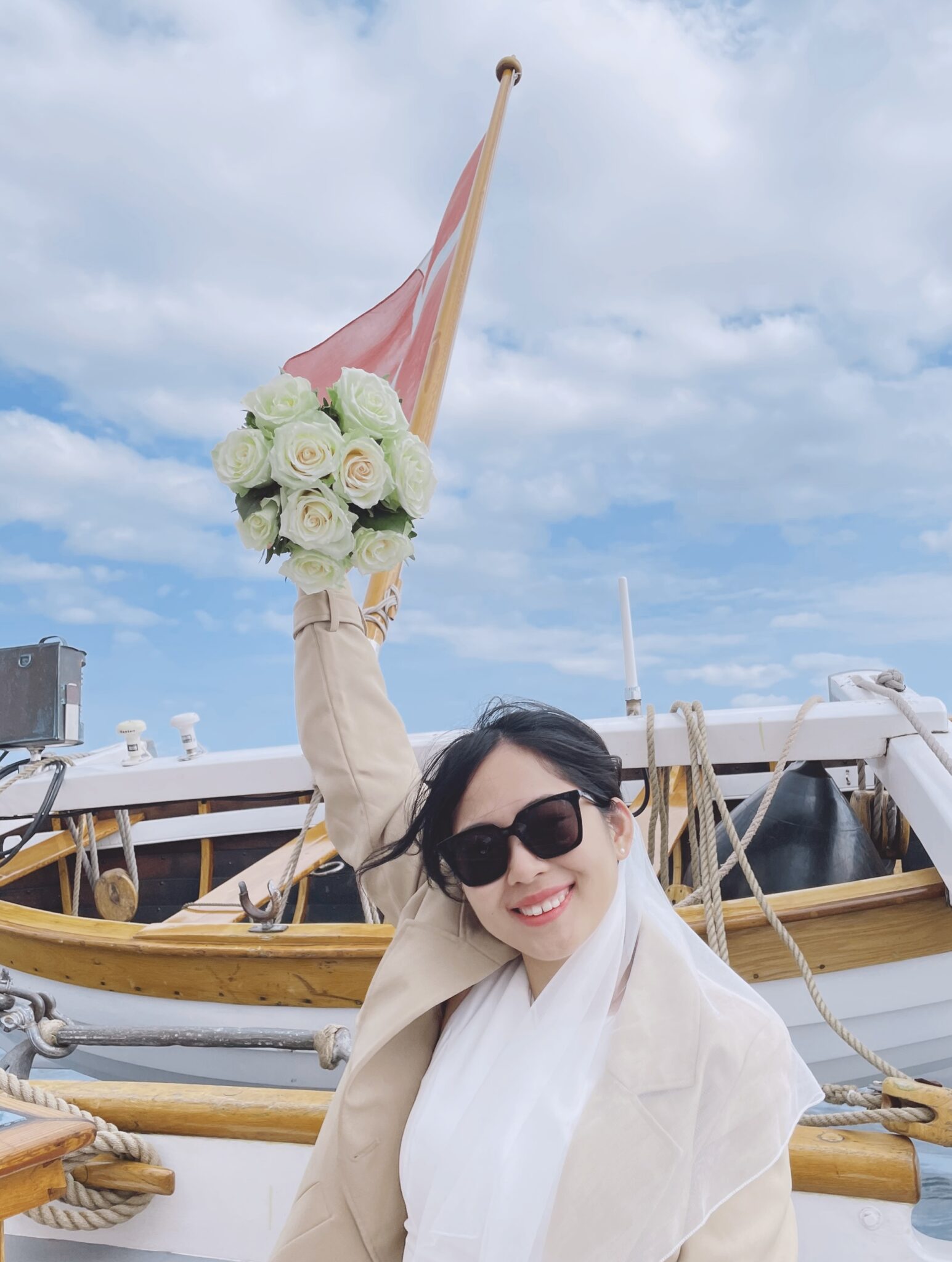 Thi Yen hebt jubelnd ihren weißen Brautstrauß in die Höhe, Glücksmoment auf dem Boot.