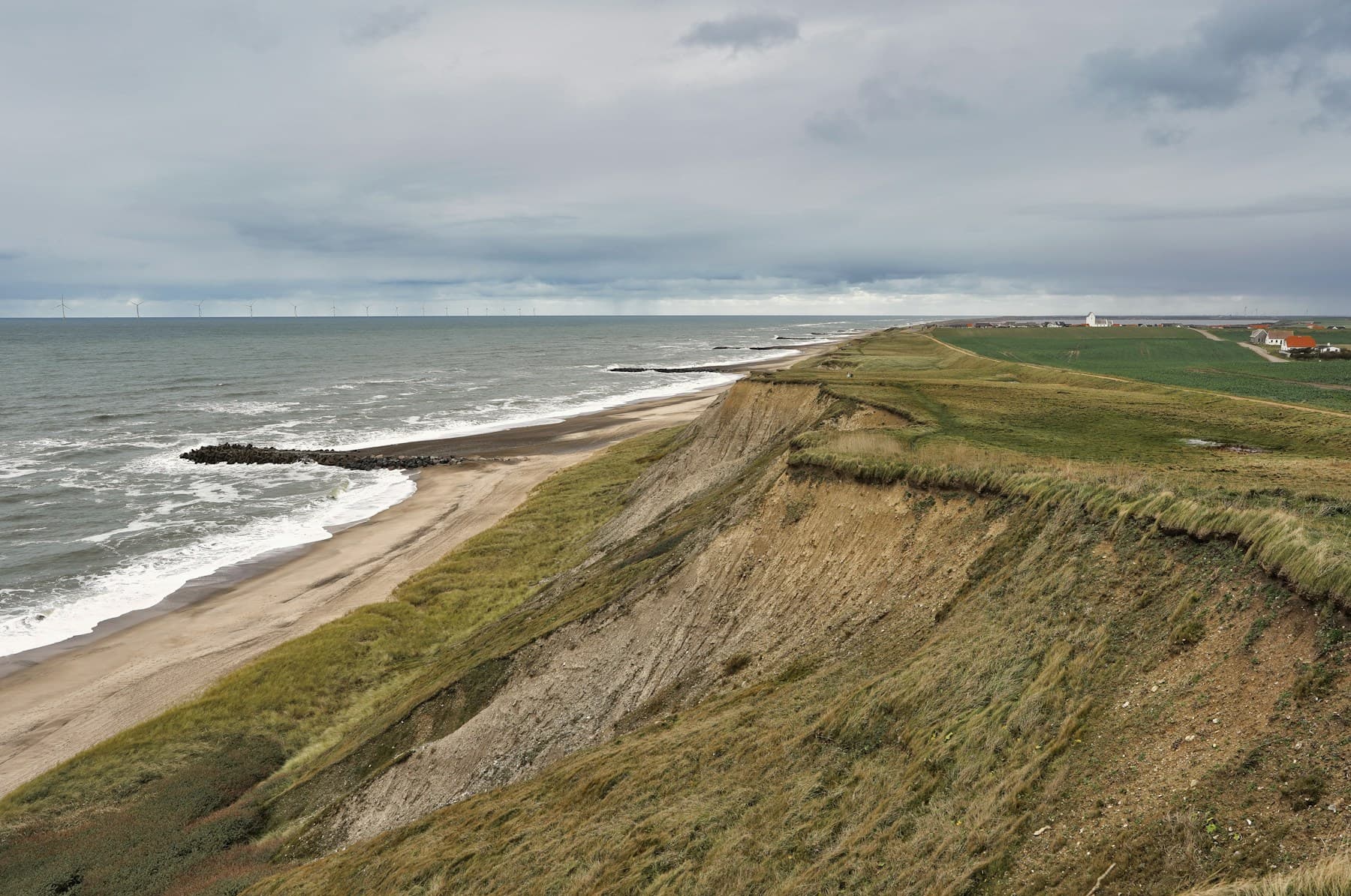 Küstenklippen mit Wellen und grünem Gras